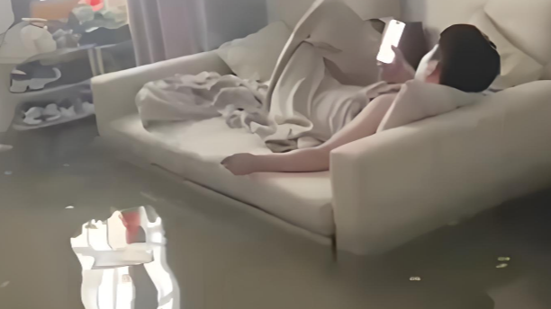 暴雨淹了家 夫妻俩1个玩手机1个补觉