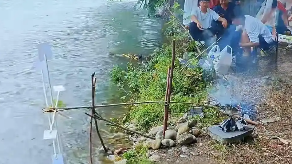 女子在河边自制烤鱼机