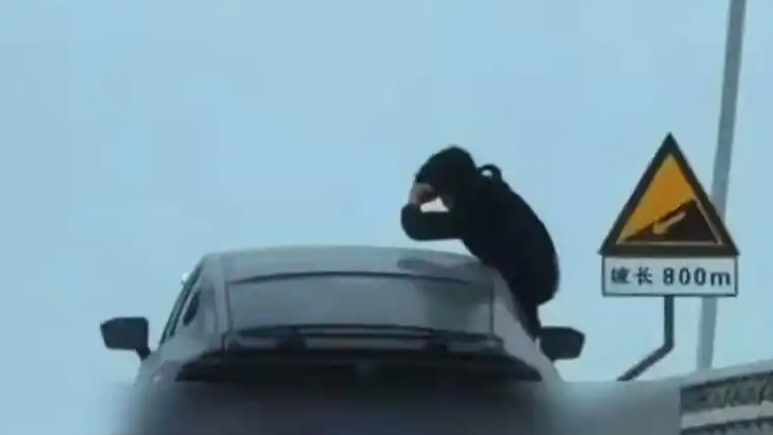  男子从行驶车辆中探身拍摄 网友举报