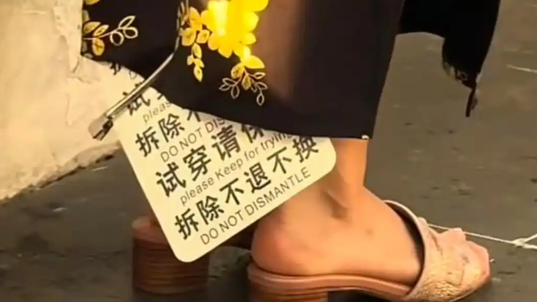 女子穿着带有巨大吊牌旗袍街头拍照
